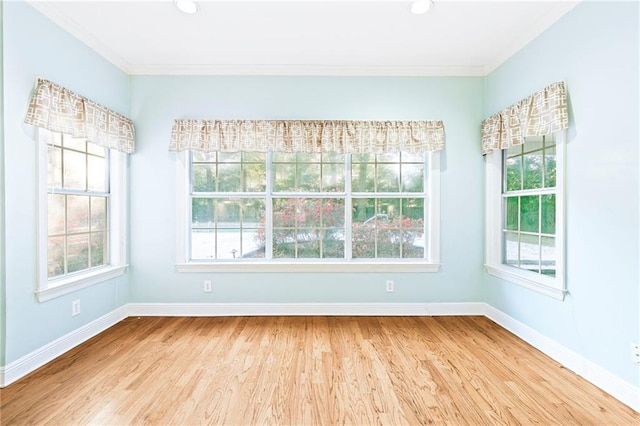 empty room featuring hardwood / wood-style floors, ornamental molding, and a wealth of natural light