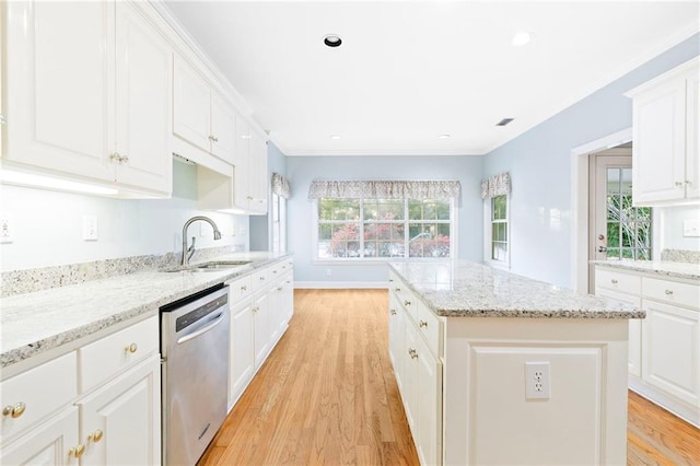 kitchen with stainless steel dishwasher, a kitchen island, white cabinetry, and sink