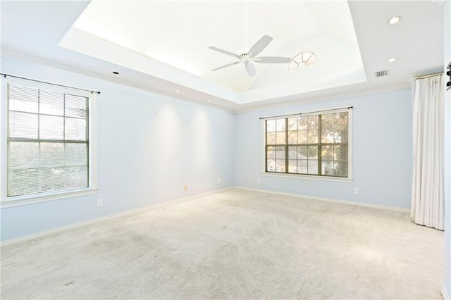 unfurnished room with a tray ceiling, ceiling fan, and light colored carpet