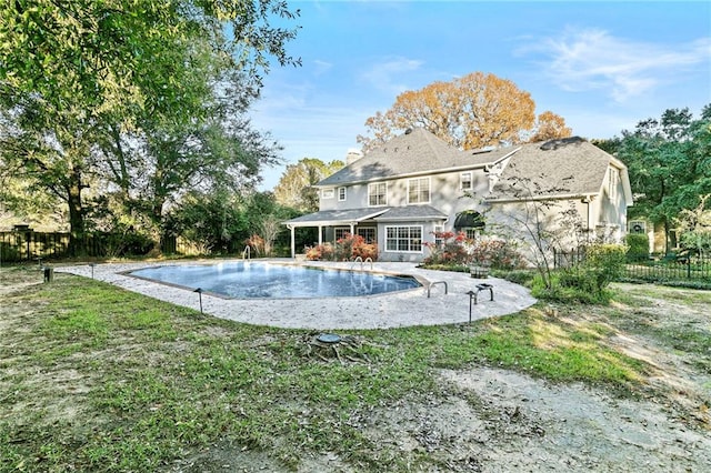 back of property featuring a yard and a fenced in pool