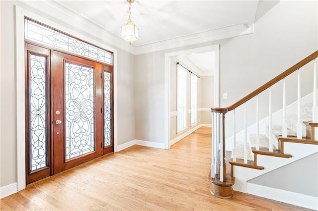 foyer entrance featuring a chandelier, light wood-type flooring, and ornamental molding