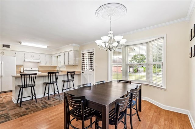 dining area with crown molding, a notable chandelier, sink, and light wood-type flooring