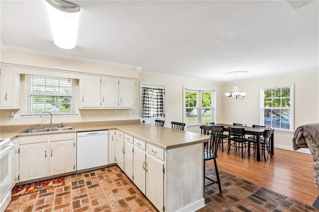 kitchen featuring sink, white appliances, white cabinetry, hanging light fixtures, and kitchen peninsula