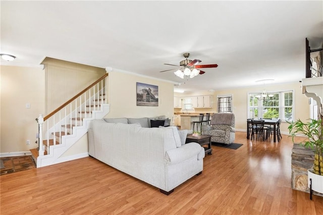 living room with wood-type flooring, ceiling fan with notable chandelier, and crown molding