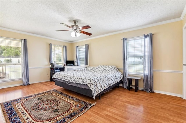 bedroom featuring ceiling fan, ornamental molding, light hardwood / wood-style floors, and a textured ceiling