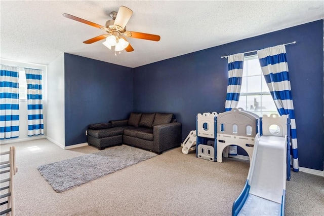 carpeted living room featuring ceiling fan and a textured ceiling