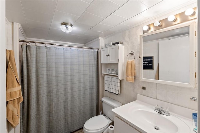 bathroom with vanity, toilet, tile walls, and walk in shower