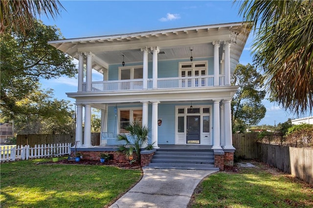 view of front facade featuring covered porch, a balcony, and a front lawn