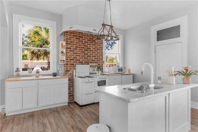 kitchen featuring white cabinetry, sink, hanging light fixtures, a chandelier, and light wood-type flooring