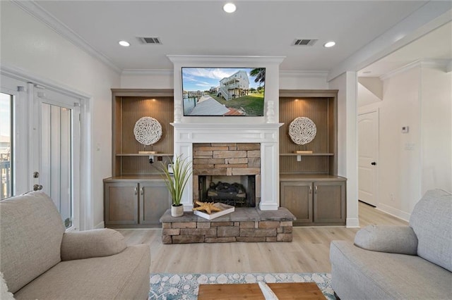 living room featuring light wood-type flooring, a stone fireplace, and crown molding