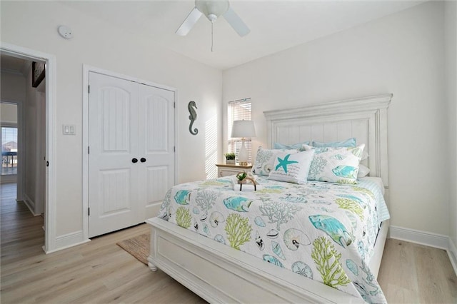 bedroom featuring multiple windows, light hardwood / wood-style flooring, a closet, and ceiling fan