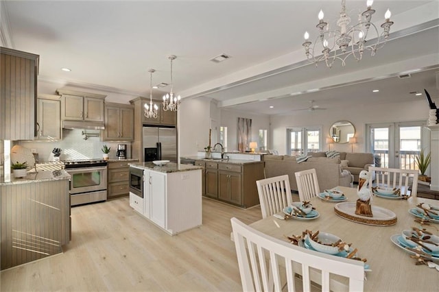 kitchen with light stone countertops, a center island, stainless steel appliances, decorative light fixtures, and ceiling fan with notable chandelier