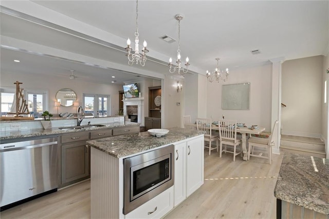 kitchen featuring sink, white cabinets, decorative light fixtures, and appliances with stainless steel finishes