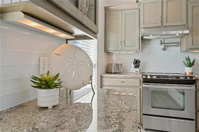 kitchen featuring decorative backsplash, light stone countertops, and stainless steel range