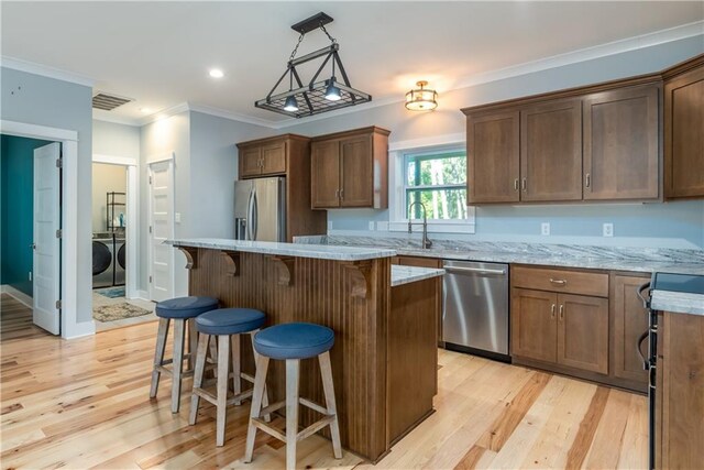 kitchen with light hardwood / wood-style floors, a center island, stainless steel appliances, and separate washer and dryer