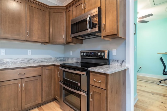 kitchen with light stone countertops, appliances with stainless steel finishes, and light hardwood / wood-style flooring