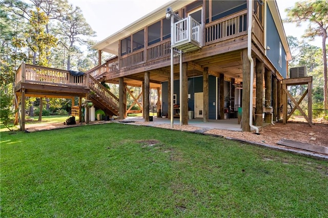 rear view of property featuring a sunroom, a patio area, a deck, and a lawn