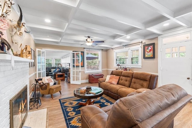 living area with beamed ceiling, ceiling fan, coffered ceiling, and wood finished floors