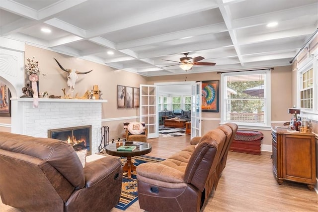 living area with a fireplace, beam ceiling, light wood-style floors, and coffered ceiling