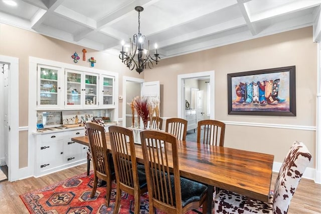 dining space with coffered ceiling, beam ceiling, light wood-style floors, and a chandelier
