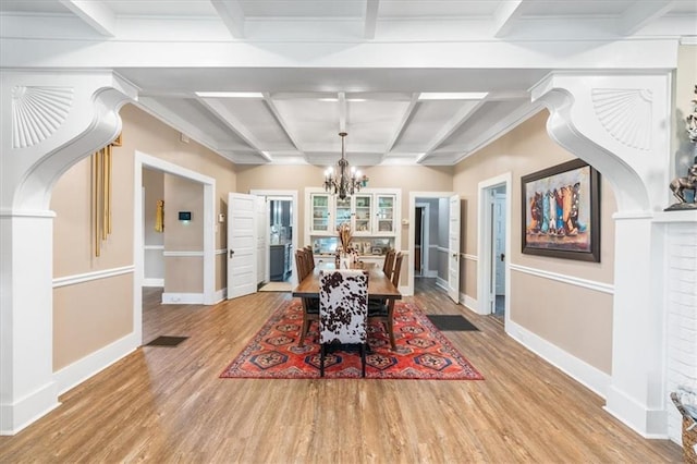 dining area featuring an inviting chandelier, wood finished floors, coffered ceiling, and baseboards