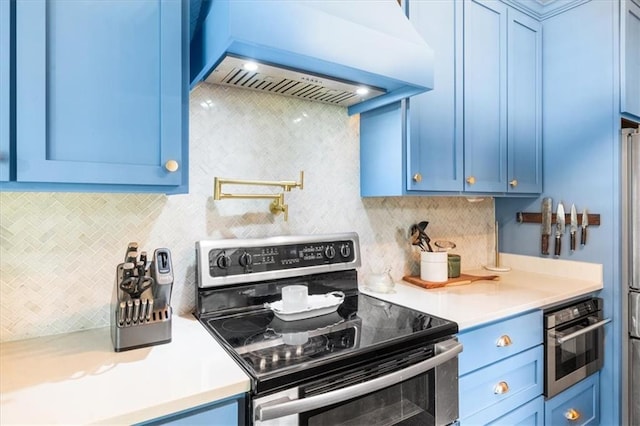 kitchen with backsplash, custom range hood, blue cabinets, and stainless steel appliances