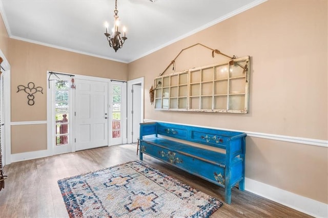 entryway featuring ornamental molding, wood finished floors, a chandelier, and baseboards