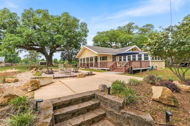 rear view of property with fence, a deck, and a patio