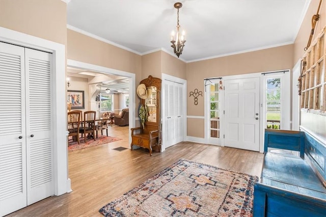 foyer featuring crown molding, an inviting chandelier, a wealth of natural light, and wood finished floors