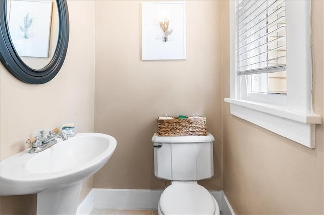 half bath featuring toilet, a sink, and baseboards