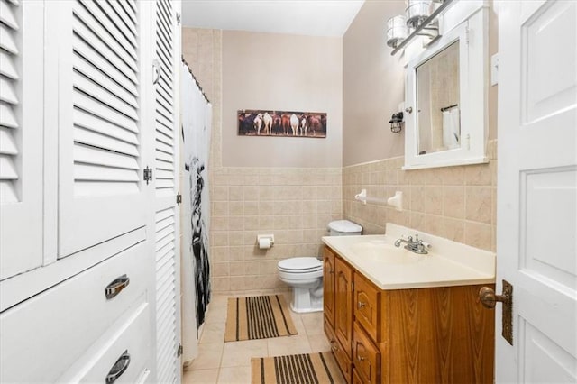 bathroom featuring a wainscoted wall, toilet, tile walls, tile patterned floors, and vanity