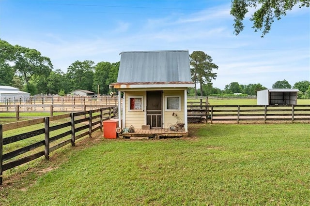 view of outdoor structure featuring fence, a rural view, and an outdoor structure