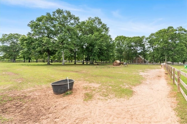 view of yard featuring an outdoor fire pit, a rural view, and fence