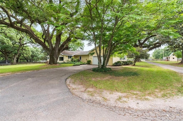 ranch-style house featuring fence, a front lawn, driveway, and an attached garage