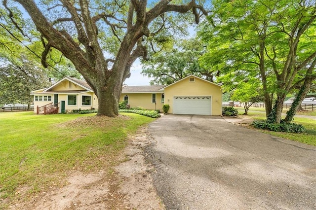ranch-style home with a front yard, fence, a garage, and aphalt driveway