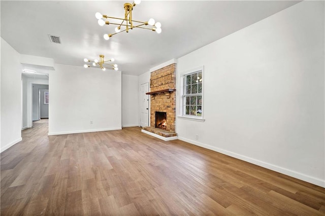 unfurnished living room featuring a chandelier, hardwood / wood-style flooring, and a fireplace