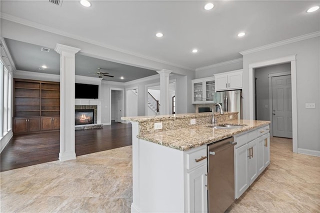 kitchen with ceiling fan, a kitchen island with sink, sink, and white cabinetry