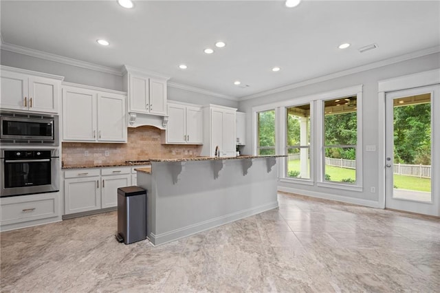 kitchen with a breakfast bar area, light stone countertops, stainless steel appliances, and white cabinets