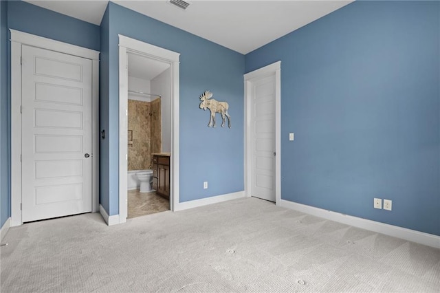 unfurnished bedroom featuring light colored carpet and ensuite bath