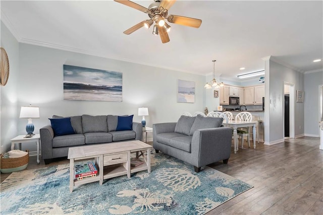 living room featuring hardwood / wood-style flooring, ceiling fan with notable chandelier, and ornamental molding