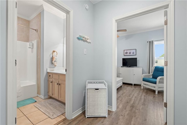 bathroom with ornamental molding, wood-type flooring, vanity, and tiled shower / bath