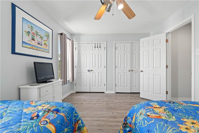 bedroom featuring multiple closets, light hardwood / wood-style floors, and ceiling fan