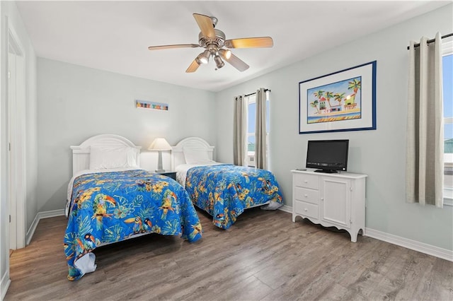 bedroom featuring hardwood / wood-style floors, ceiling fan, and multiple windows