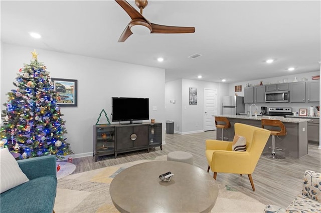 living room with light hardwood / wood-style floors, ceiling fan, and sink