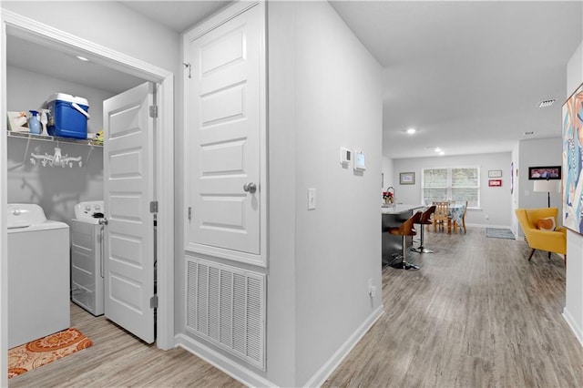 hallway with washing machine and dryer and light hardwood / wood-style flooring