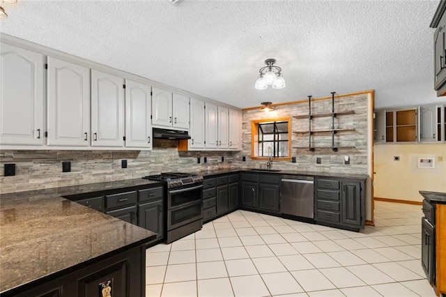 kitchen featuring appliances with stainless steel finishes, backsplash, dark stone counters, sink, and white cabinetry