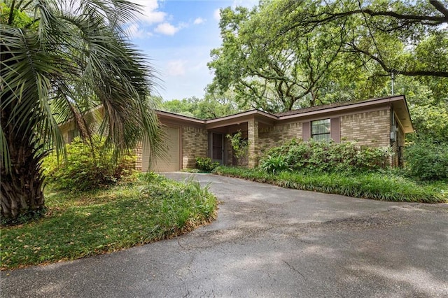 view of front of property featuring a garage, brick siding, and driveway