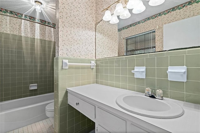 bathroom featuring wallpapered walls, tile walls, tile patterned flooring, and a notable chandelier
