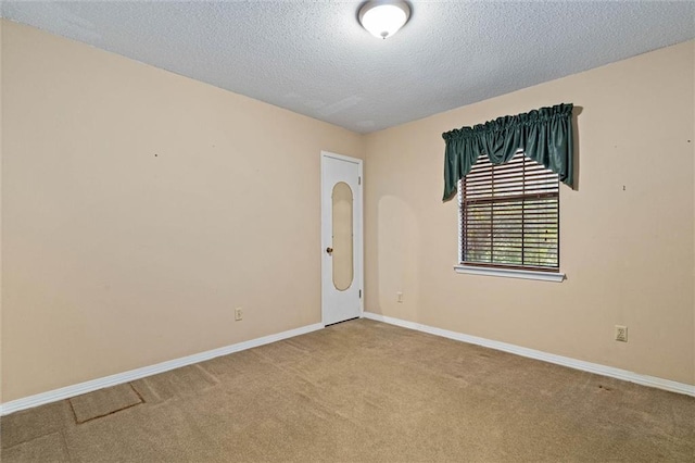 carpeted empty room with a textured ceiling and baseboards