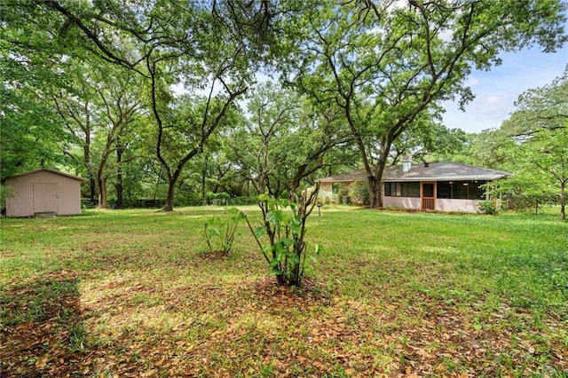 view of yard featuring a sunroom, a shed, and an outbuilding